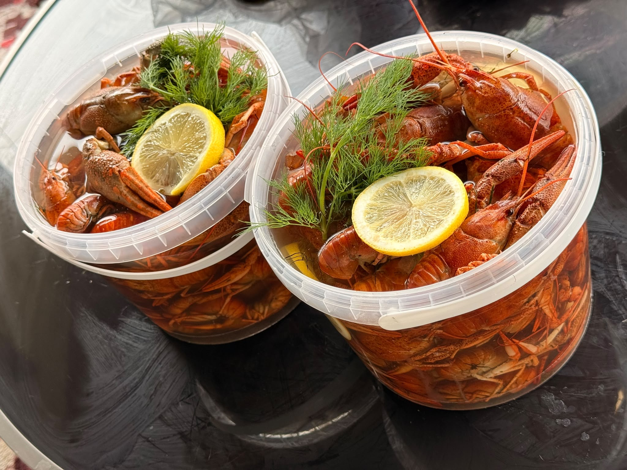 Наши варёные раки в прозрачных вёдрах с рассолом, укропом и лимоном